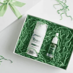 Gift box with green tissue/shred containing HempWell Deep Relief spray and CBD oil bottle for gift presenting health products.